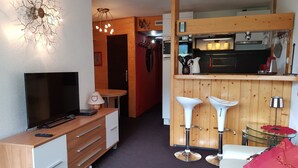 A compact living space with a TV, wooden furniture, a kitchenette, and a dining area with stools. - Comfortable 2-room apartment in Arc 2000 for 6 people (Les Arcs 2000)