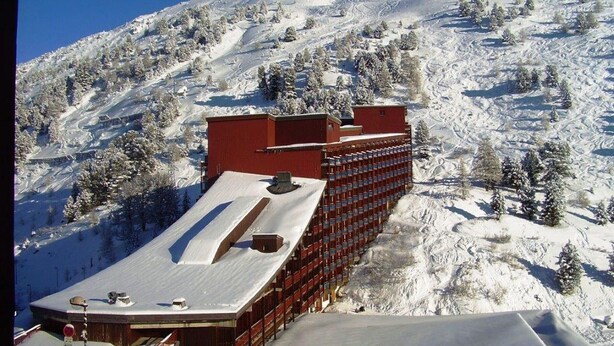 A hotel with a red facade and multiple floors, situated on a snowy mountain slope. - Comfortable 2-room apartment in Arc 2000 for 6 people (Les Arcs 2000)