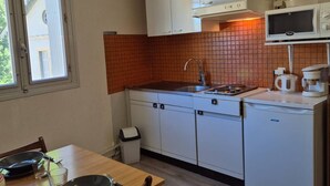 A compact kitchen with white cabinets, a tiled backsplash, a microwave, and a coffee maker.