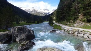 A river flowing through a mountainous area with a clear path alongside.