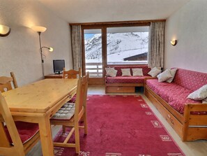 A cozy room with a wooden table, a sofa, and a window with a view of a snowy landscape.