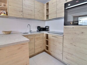 A kitchen with wooden cabinets, a stainless steel sink, a Bosch refrigerator, and a coffee maker.