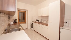 A kitchen with white cabinets, a microwave, a kettle, and a sink. - Raisa Apartments (Pressbaum)