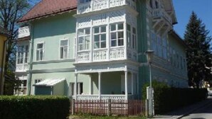 A two-story house with a balcony and a red roof. - Raisa Apartments (Pressbaum)