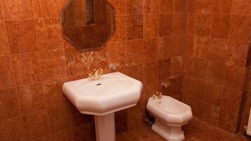 A bathroom with a pedestal sink, a toilet, and a mirror on the wall.