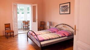 A bedroom with a bed, a chair, a desk, and a door leading to a balcony. - Raisa Apartments (Pressbaum)