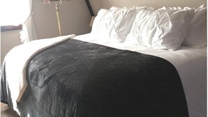 Un dormitorio con cama, lámpara y ventana con cortinas.