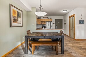 Ein Essbereich mit Holztisch und Stühlen, einer Hängelampe und einer Küche im Hintergrund.