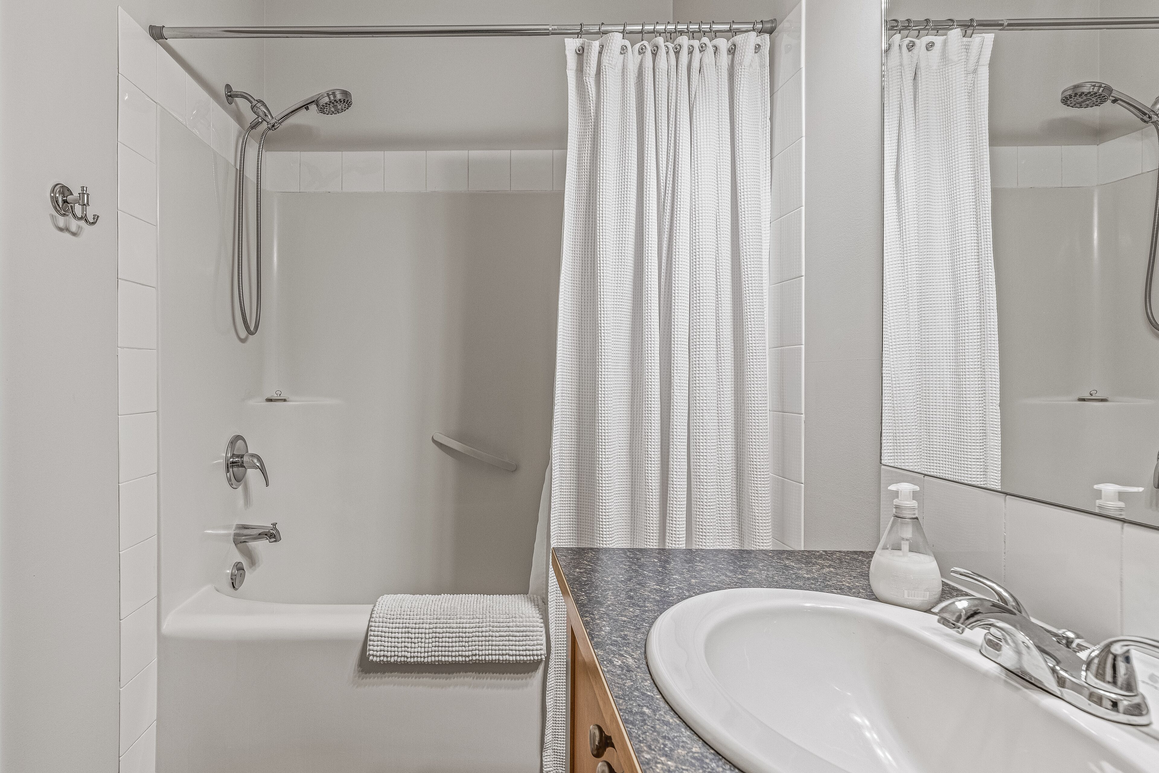 A modern bathroom with a shower, a bathtub, a sink, and a mirror.