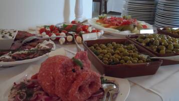 A buffet with various food items including meats, cheeses, and olives.