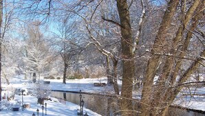 A snow-covered park with a canal, benches, and lampposts. - Land Gut Hotel Weisser Schwan (Zossen)