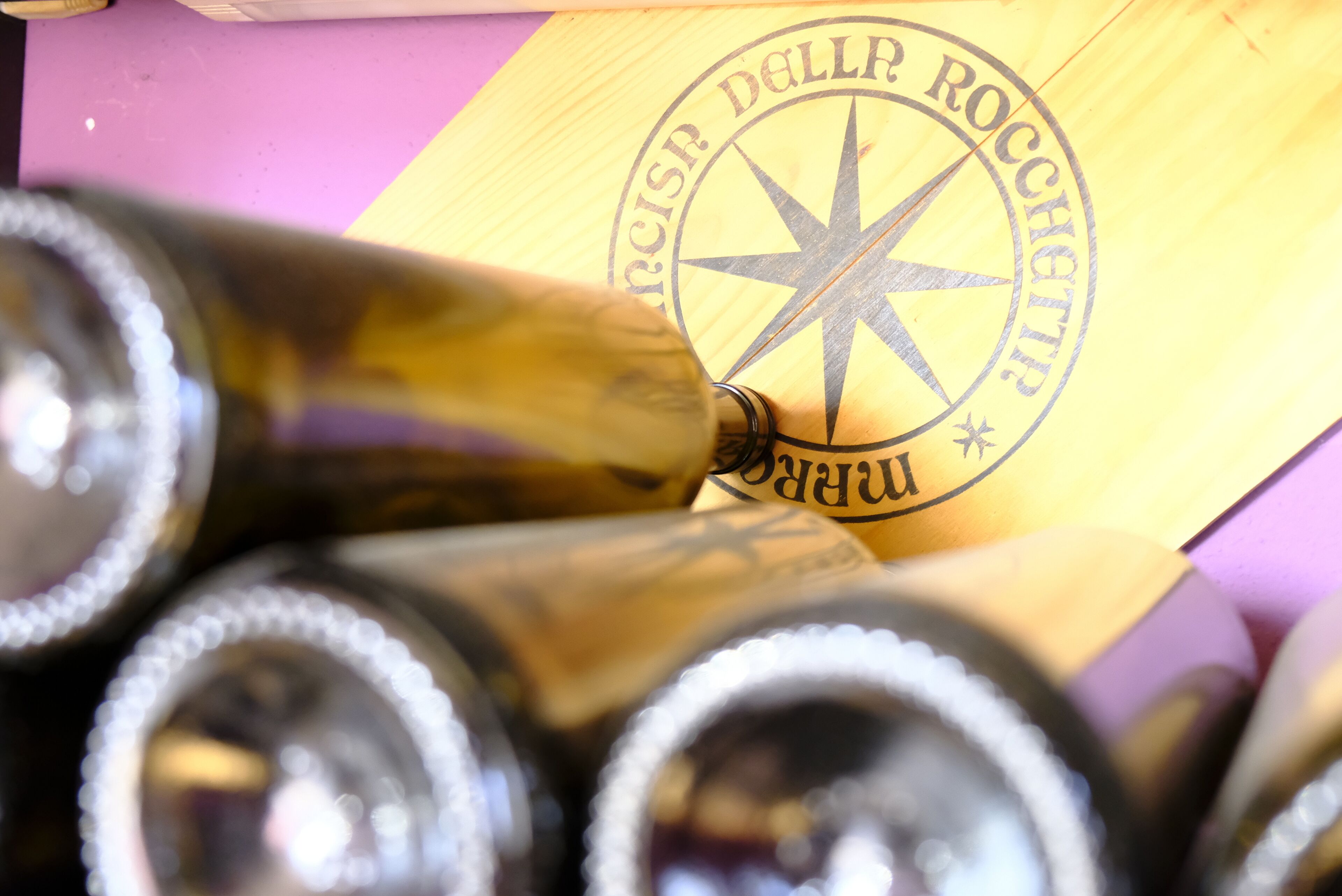 A wooden box with a star emblem and text, containing several bottles.