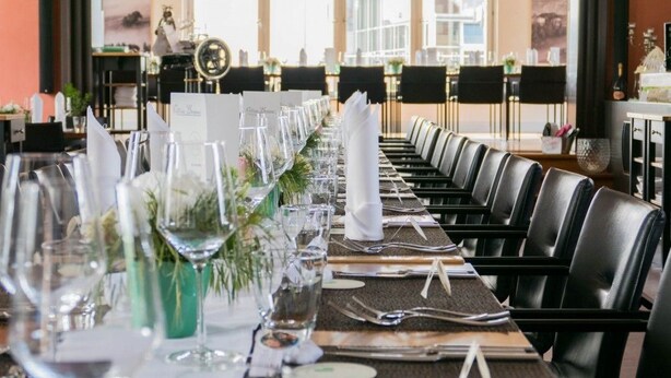 A long dining table set with chairs, glassware, and floral centerpieces, suggesting a formal dining area in a hotel. - Villa Behr (Wendlingen am Neckar)