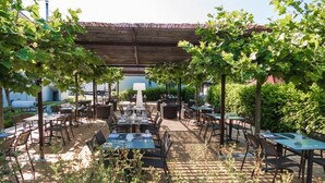 An outdoor dining area with tables and chairs, surrounded by greenery and a covered structure. - Villa Behr (Wendlingen am Neckar)