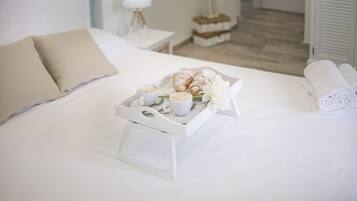 Una cama bien hecha con una bandeja de pasteles y tazas de café, una almohada blanca y una toalla enrollada al lado.