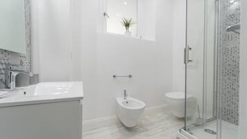 Et moderne badeværelse med bruser, toilet og pissoir.