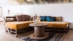 Un cuarto acogedor con un sofá de madera, una mesa redonda de madera y un mural con un paisaje urbano en la pared.