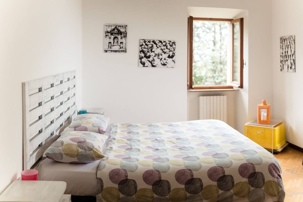 Une chambre à coucher avec un lit, une fenêtre, un radiateur, une petite table et une chaise.