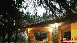 Un patio exterior con pilares de piedra, una mesa de metal y sillas.
