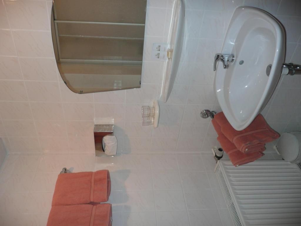 A bathroom with a white sink, a mirror, a towel rack, and a toilet.