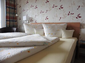 A hotel room with a bed, a chair, and a nightstand. - Pension zum Fernblick (Willingen)