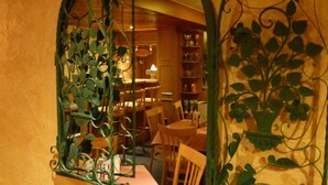 A room with a unique arched mirror with green vines, wooden furniture, and a visible dining area in the background. - Pension zum Fernblick (Willingen)