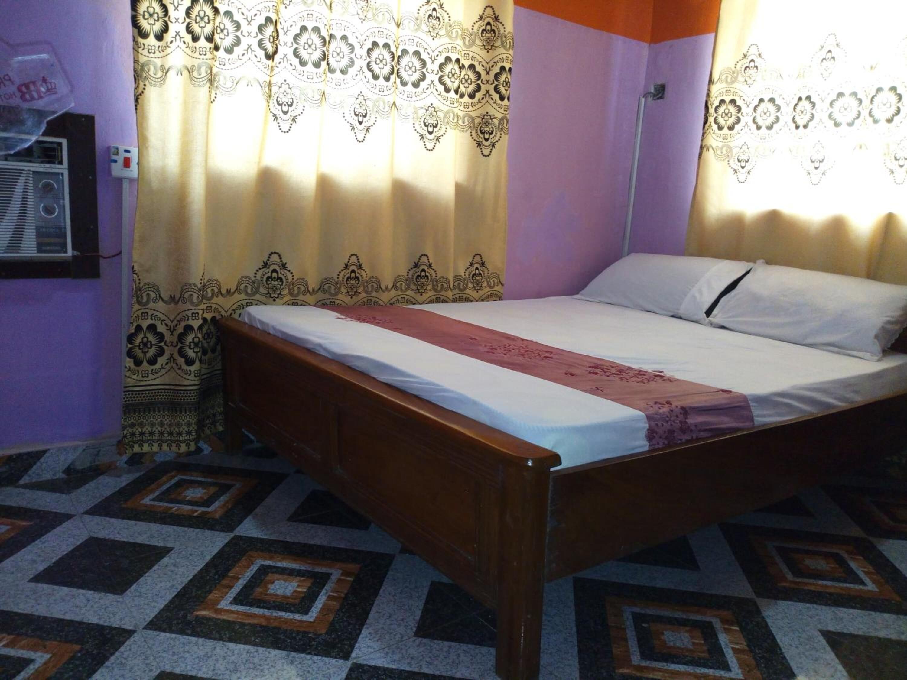 Una cama individual en una habitación con cortinas estampadas y un diseño geométrico en el suelo.