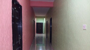 Un pasillo con una pared rosa a un lado y una pared beige al otro, que conduce a una puerta al final.