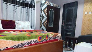 Un dormitorio con una cama de madera, un tapete estampado, un armario y una puerta.