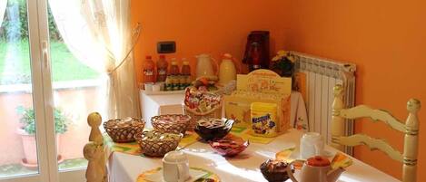 A breakfast table with various food items, a coffee maker, and a radiator.