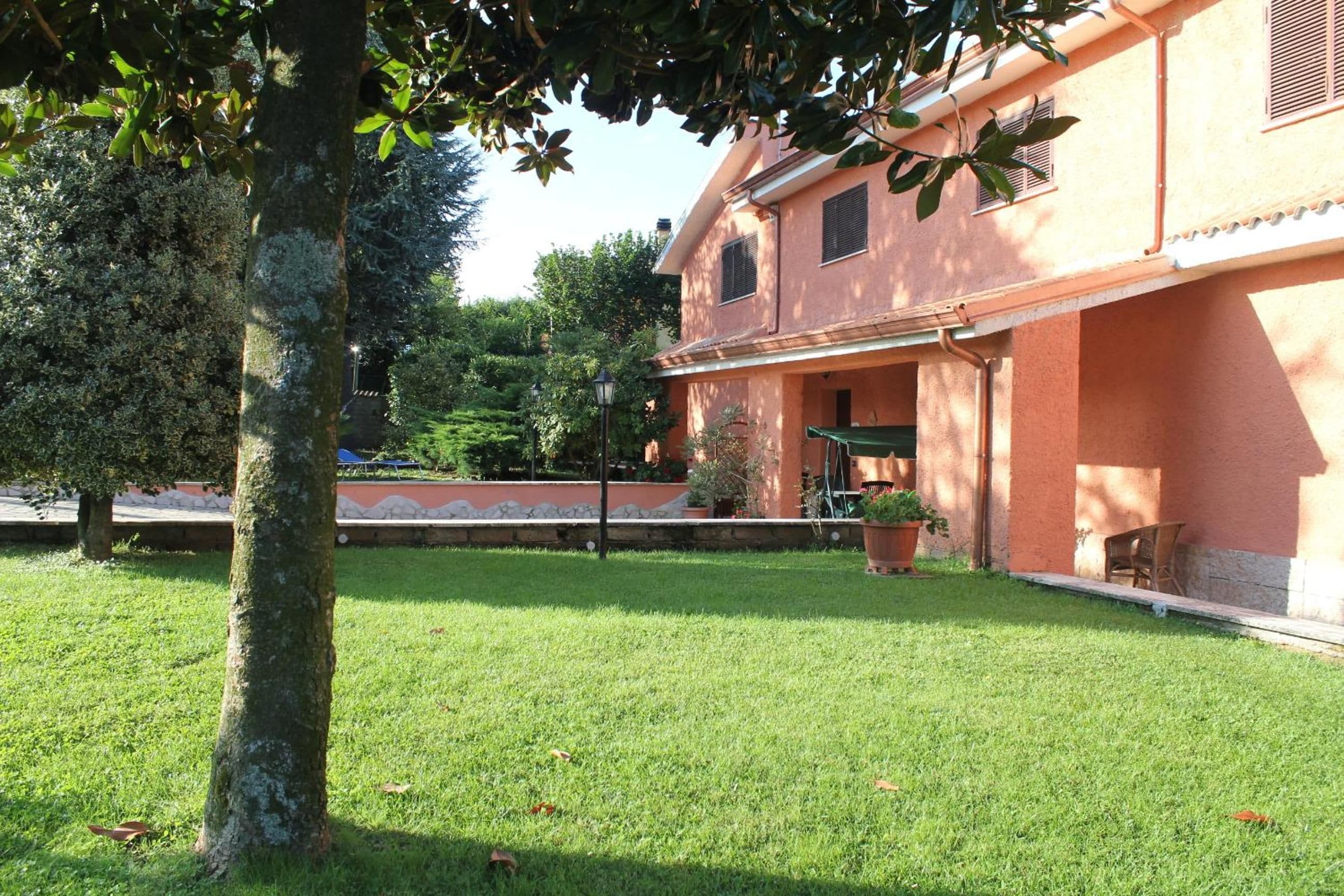 A building with a red facade, a grassy lawn, and a tree in the foreground.