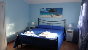 Un dormitorio con una cama, dos mesitas de noche, un cuadro y una ventana con cortinas.