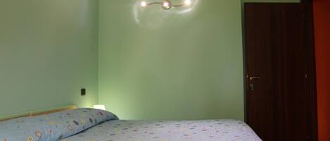 Una habitación con una cama, un accesorio de luz en la pared y una puerta.