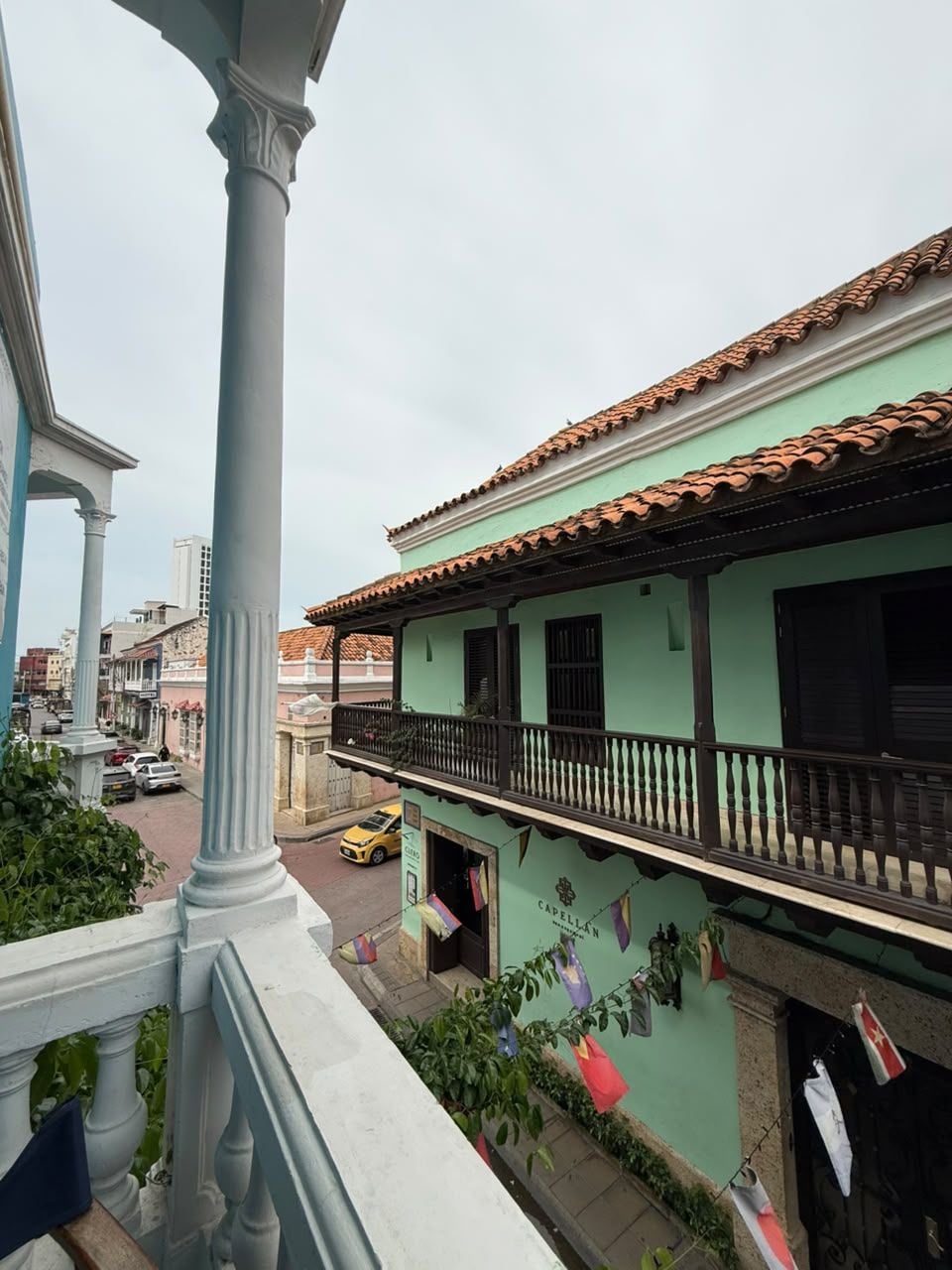 A building with a balcony, a street view, and a clear sky.