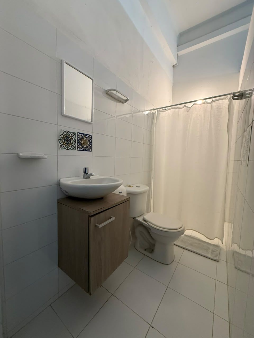 Un baño con lavamanos, inodoro y cortina de ducha.