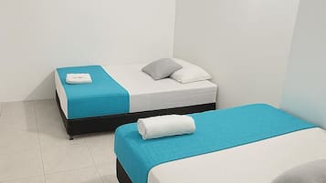 Ein Hotelzimmer mit zwei Betten, jeweils mit einer blauen Bettdecke und weißen Kissen.