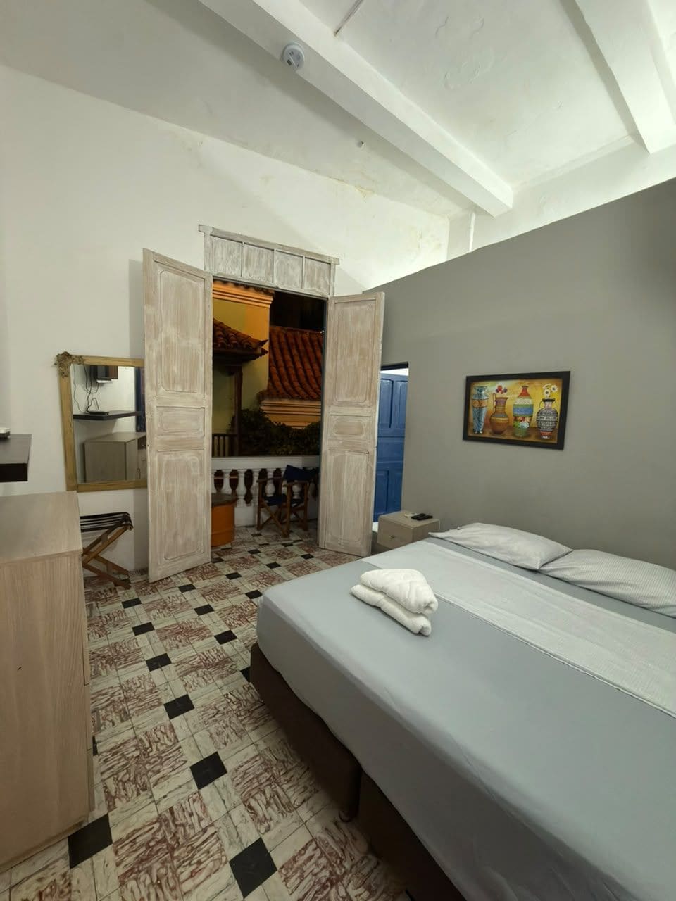 A bedroom with a bed, a wardrobe, a mirror, and a door leading to a balcony.
