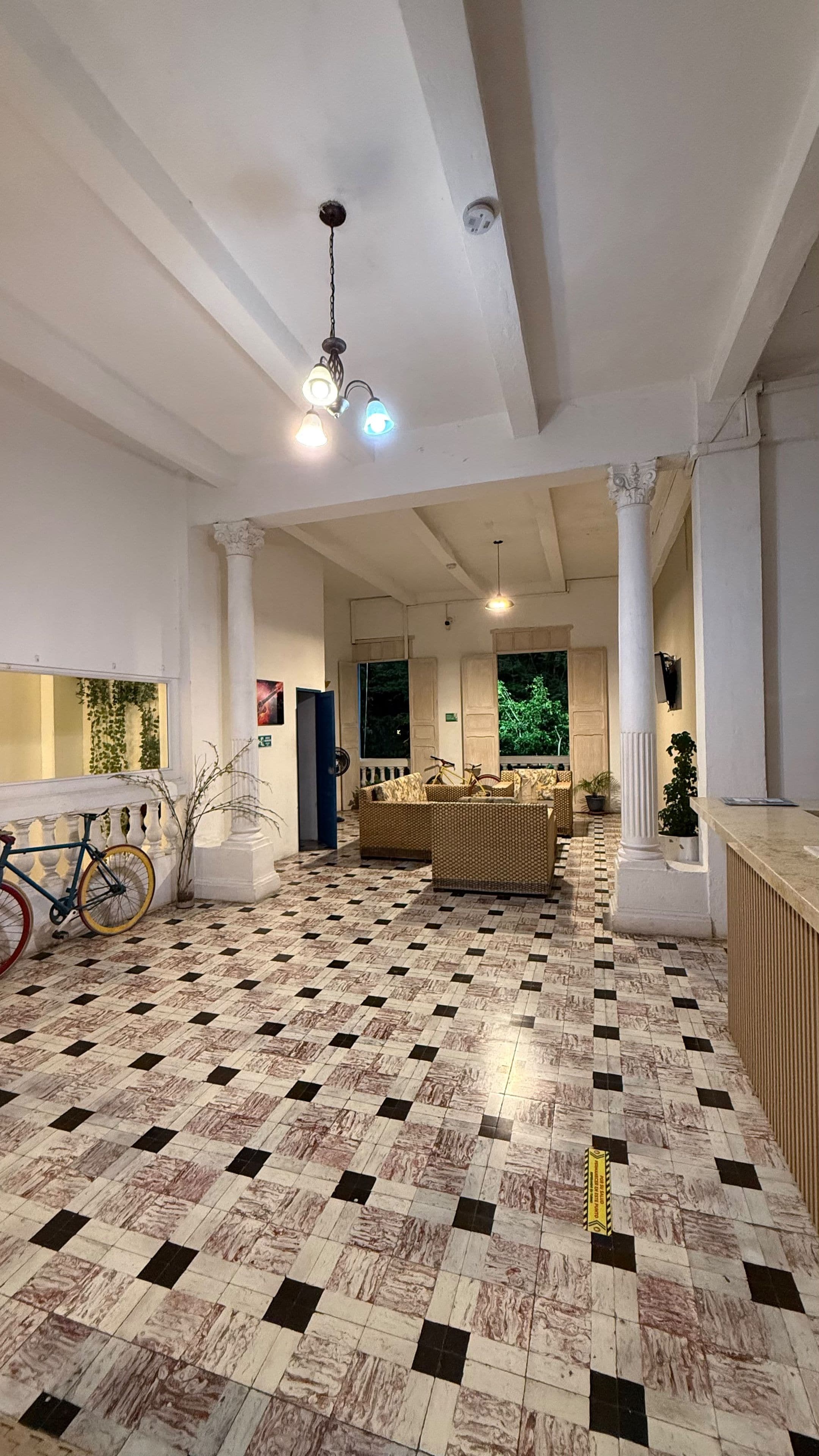 Un vestíbulo espacioso con piso de cuadros, una recepción y una bicicleta estacionada junto a la pared.