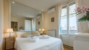 A hotel room with a large bed, two bedside lamps, a mirror, a radiator, and a window with curtains. - Efeso (Florence)