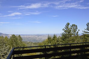 Un mirador panorámico con un banco, que ofrece amplias vistas a un valle y montañas lejanas.