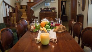 A dining table with a candle, fruits, and bread, set in a dining area with wooden chairs and a staircase in the background. - Poggio Eco B&B (Ascoli Piceno)