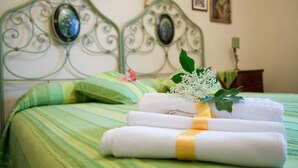 A neatly made bed with green striped bedding, a decorative metal headboard, and a small bouquet of white flowers. - Poggio Eco B&B (Ascoli Piceno)