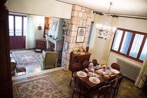 A dining area with a stone wall, a chandelier, and a view of the outside through large windows.