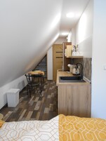 Una habitación compacta con kitchenette, comedor y cama.