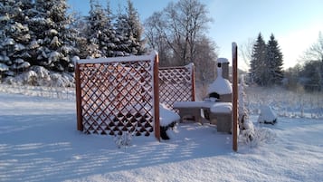 A snow-covered outdoor seating area with a lattice fence and benches.
