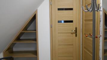 A room with a wooden door, a coat rack, and a staircase leading to an upper level.