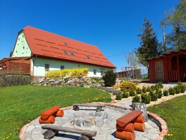 Una casa con techo rojo y fachada verde clara, rodeada de un jardín cuidado con diversas plantas y flores.