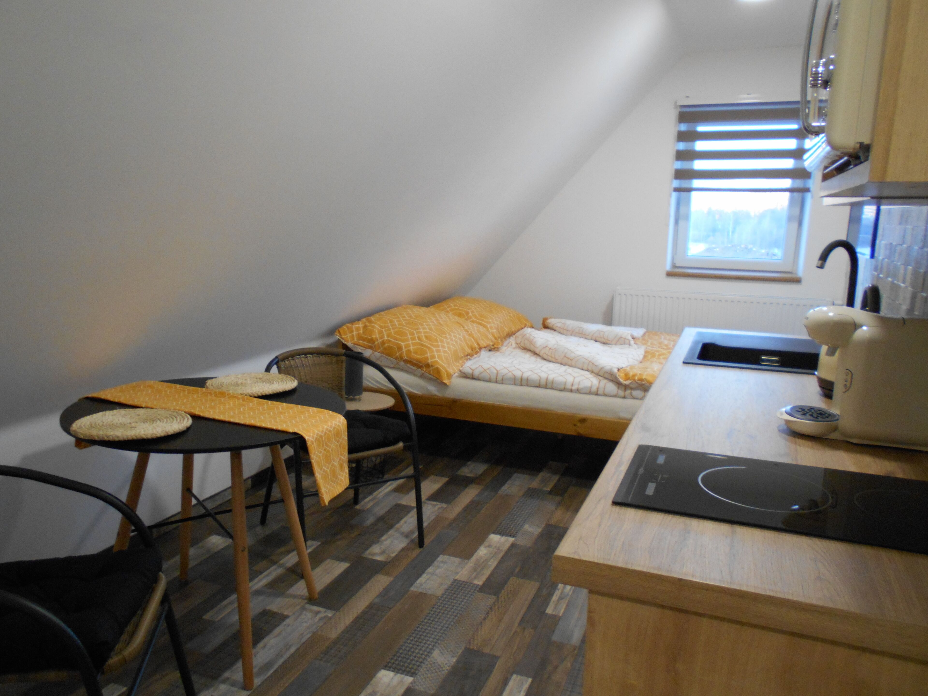 Una habitación pequeña y funcional con cama, una silla, una mesa y ventana.