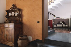Un mueble de madera con un reloj, una cesta de mimbre y una escalera que conduce a una habitación con radiador.