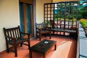 Un patio con mobiliario de madera, que incluye un banco, dos sillas y una mesita.